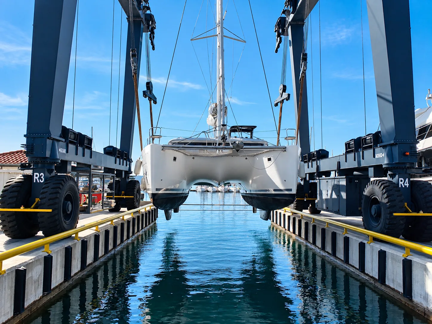 Sailing catamaran lifted between travel lifts during haul-out inspection